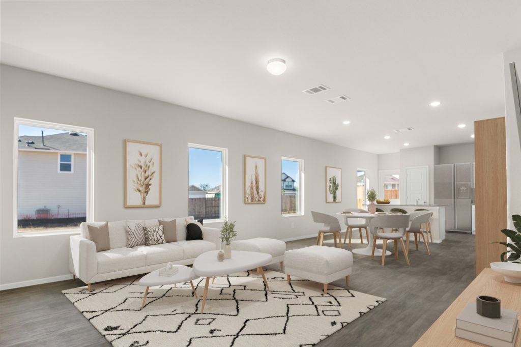 Image of a living room staged photo with a white couch and coffee tables, a white rig, wall decor, and a round dinner table
