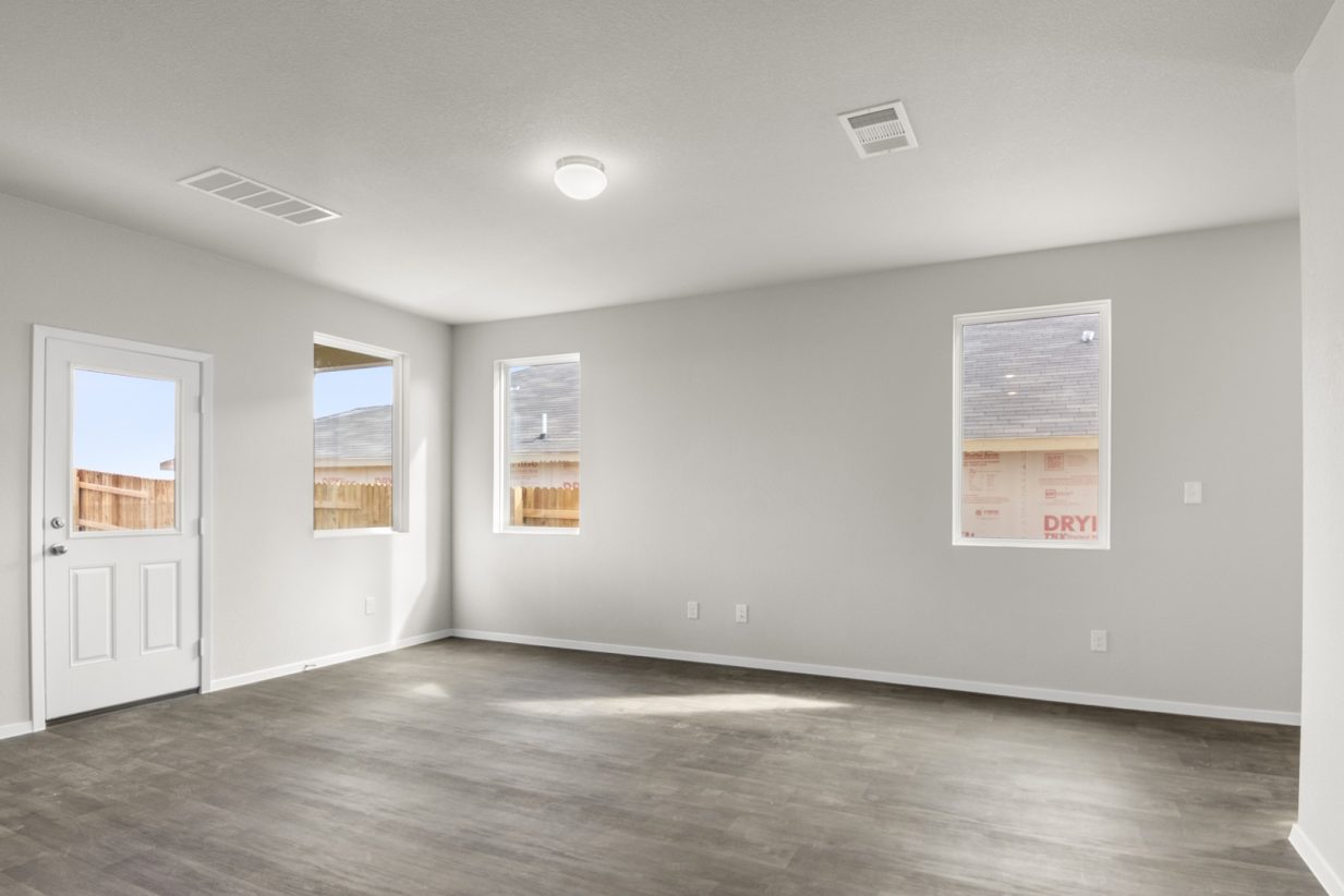 Image of a living room with light grey walls, dark brown flooring, windows and white trim