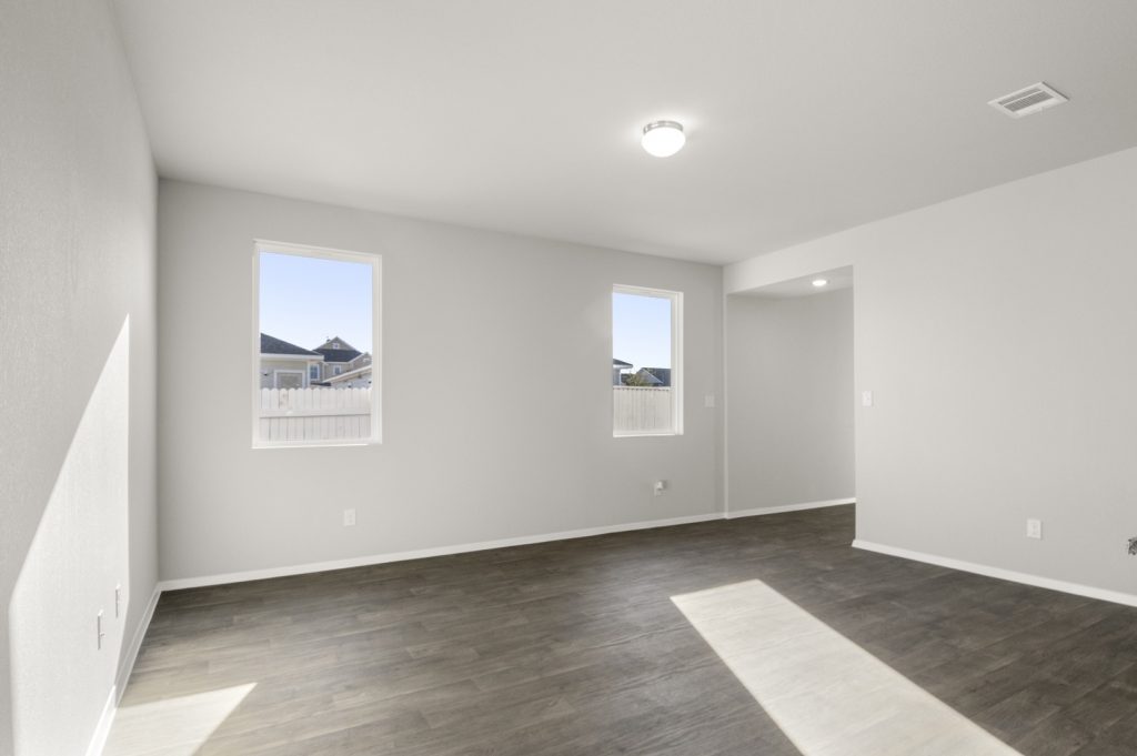 Image of a two story home living room with brown wood-like flooring and light grey painted walls with two windows