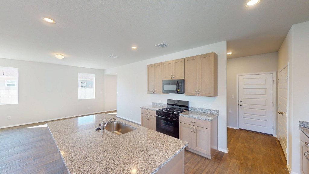 Image of a kitchen with granite countertops and brown cabinets with black appliances