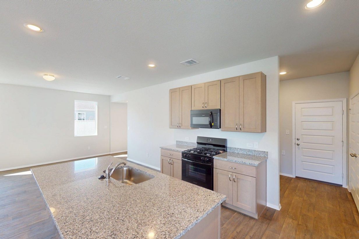 Image of a kitchen with granite countertops and brown cabinets with black appliances