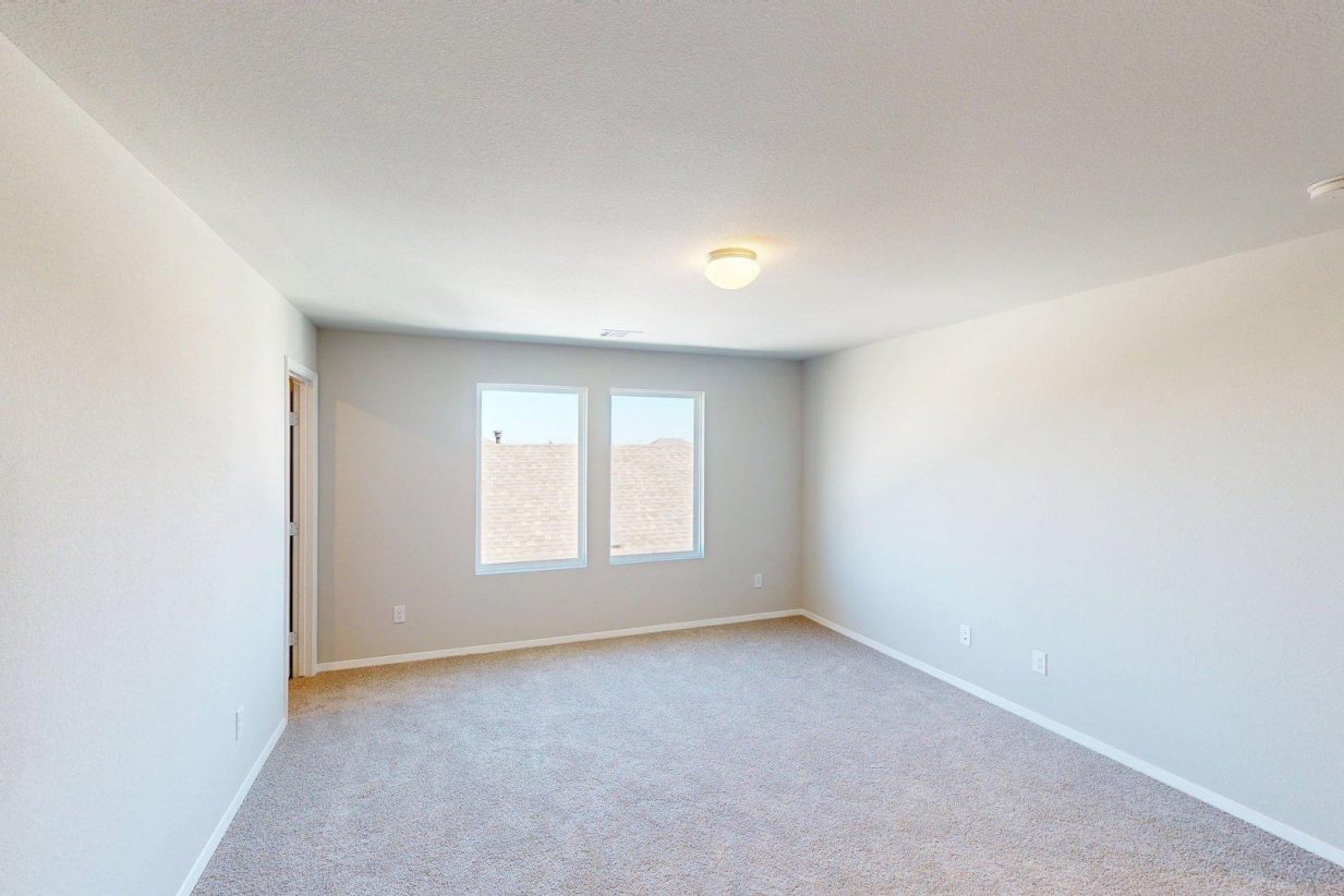 Image of flex space area with tan carpeting and light grey walls with two windows