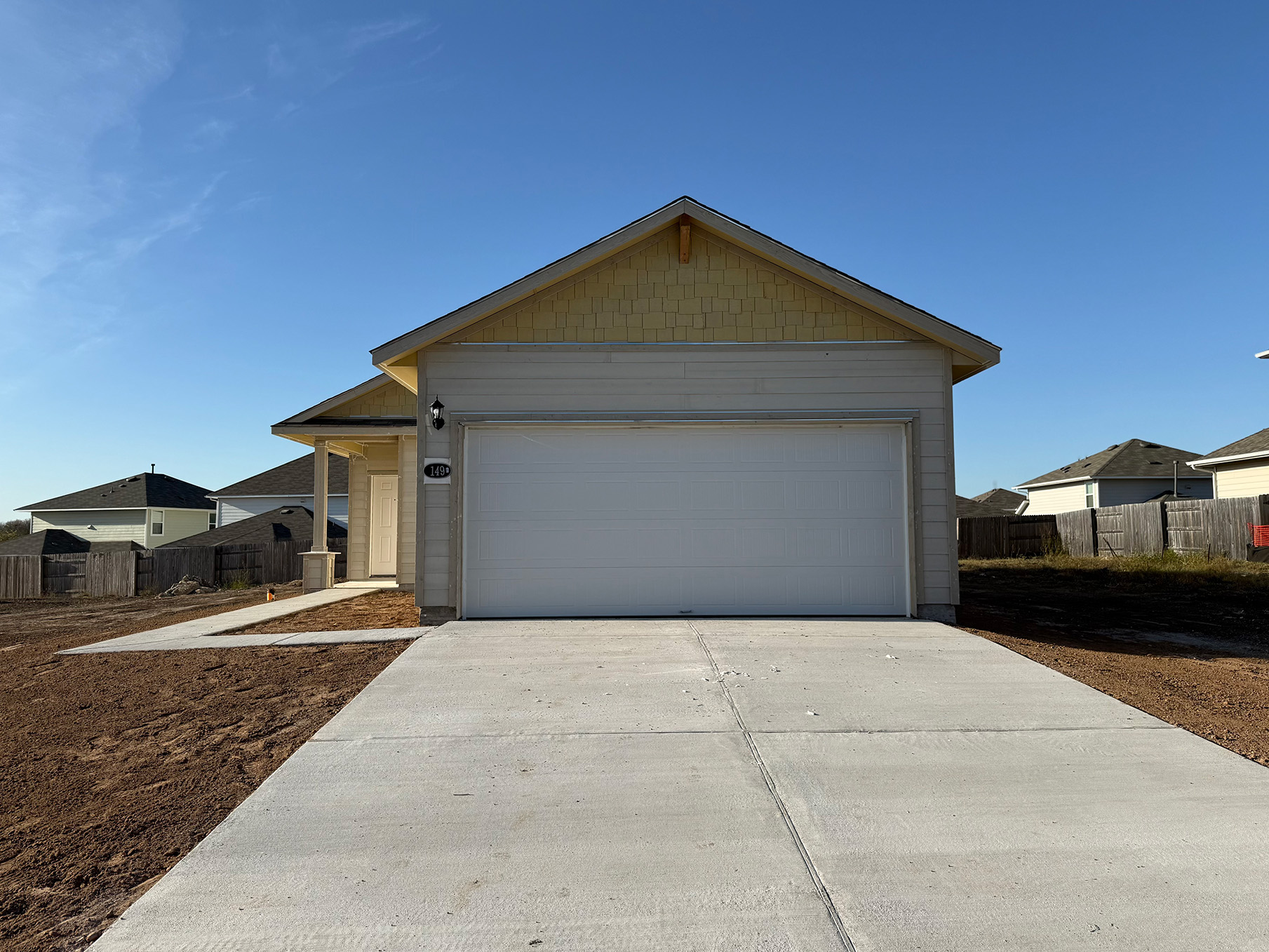 Image of the front of a construction home with yellow accents and a white garage door