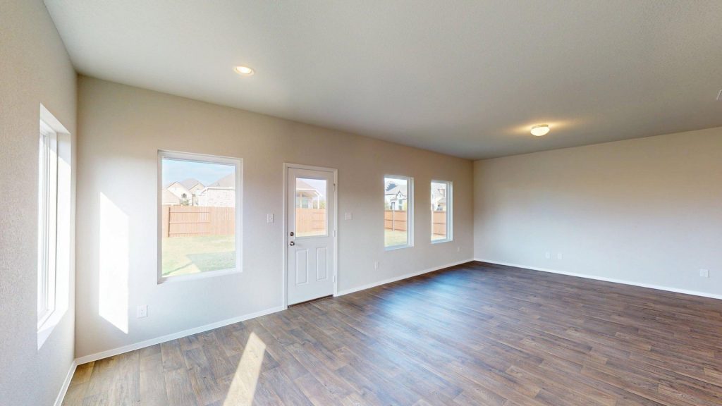 Matterport snapshot of a living room area with brown wood-look flooring and beige walls with windows