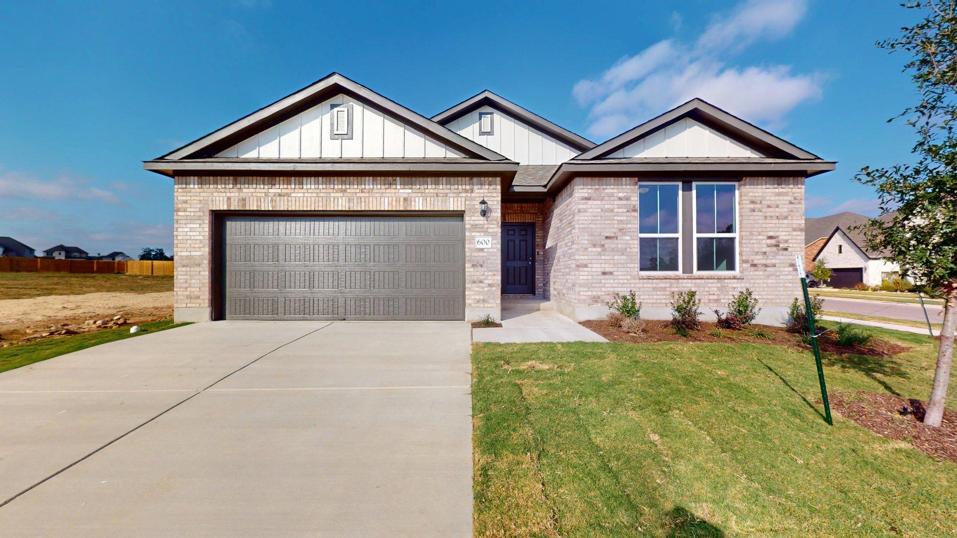 Matterport snapshot of a one story brick home exterior with a blue door, brown garage and a cement driveway