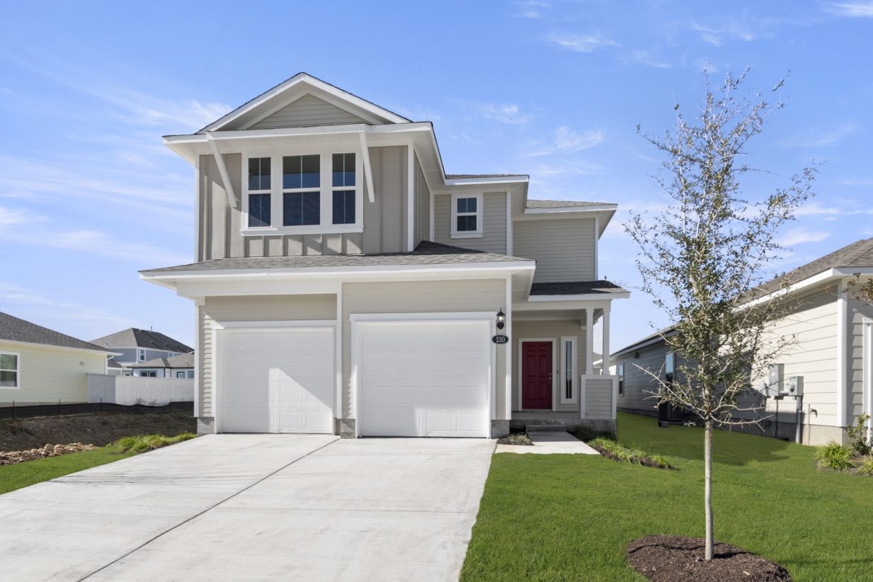Image of the front exterior of a beige two story home with a double door two car garage with a cement driveway, white trim and a red front door