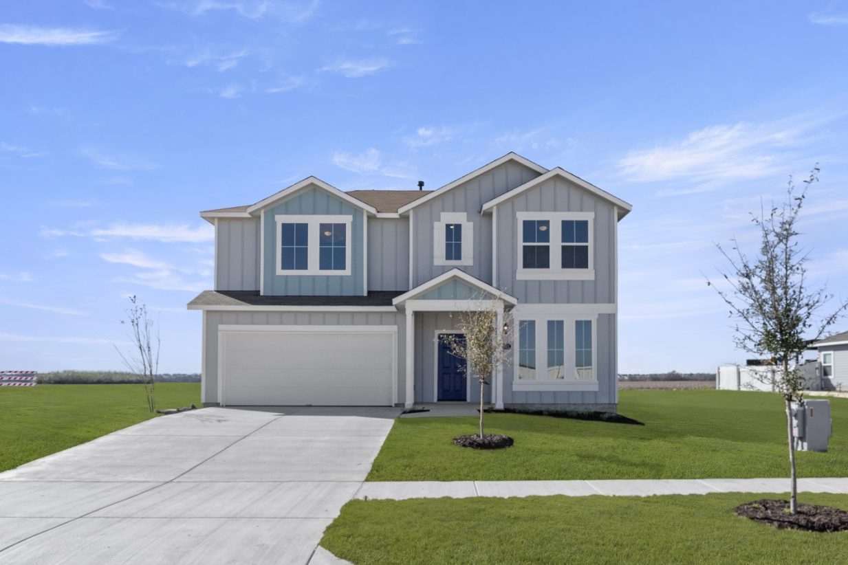 Image of a light blue two story house with white trim and garage door, a royal blue front foor, a cement driveway, green grass front yard and a blue sky in the distance