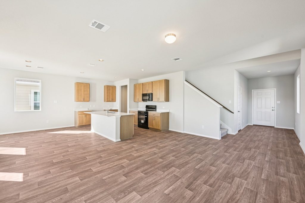 Image of a kitchen and living room area with grey walls, vinyl flooring and a staircase