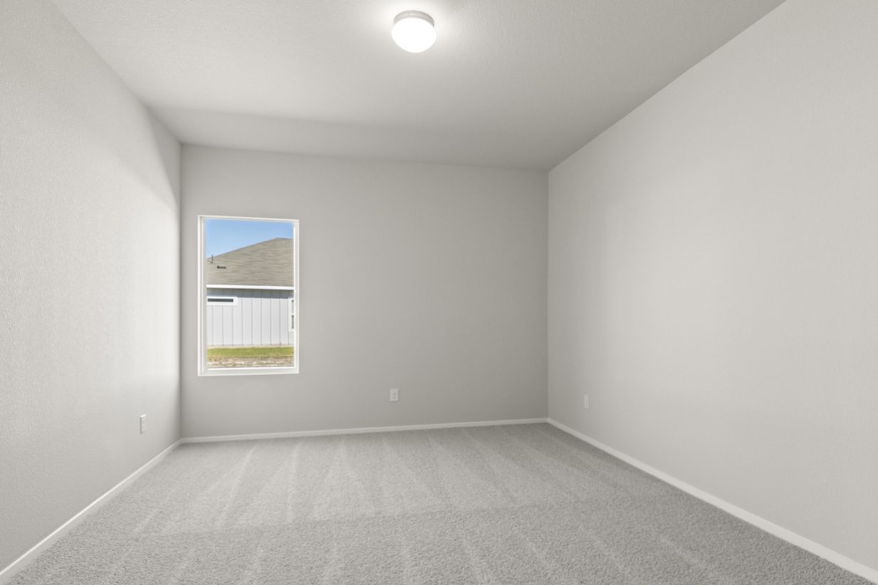 Image of a flex space with light grey walls, tan carpeting, a window and white trim