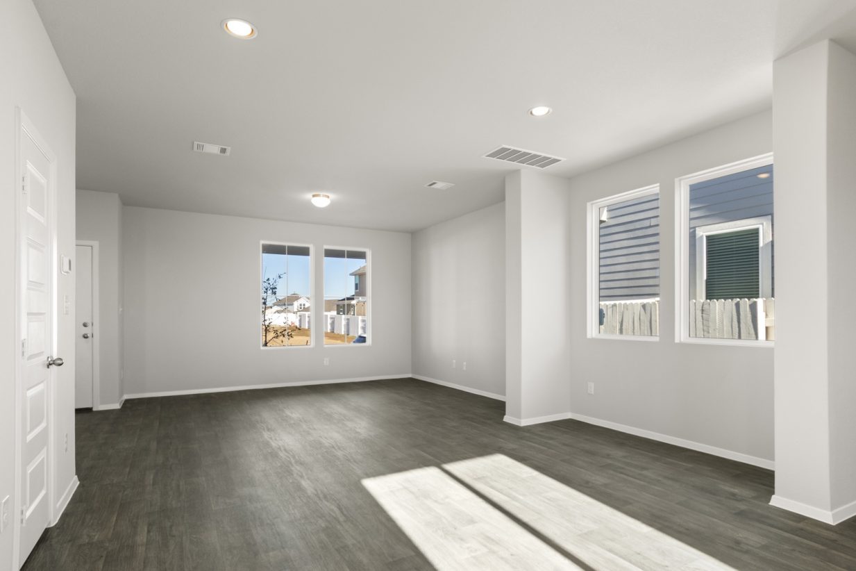 Image of a dining room with light grey walls, dark vinyl flooring, and windows
