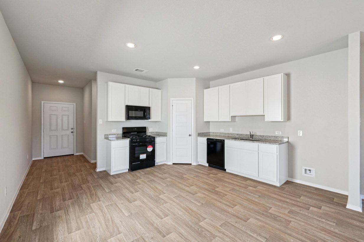 Image of a kitchen with white cabinets, a corner pantry, and black appliances