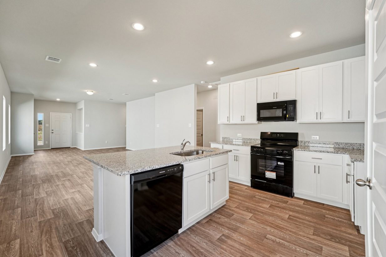 Image of a kitchen with a center island, white cabinets and black appliances