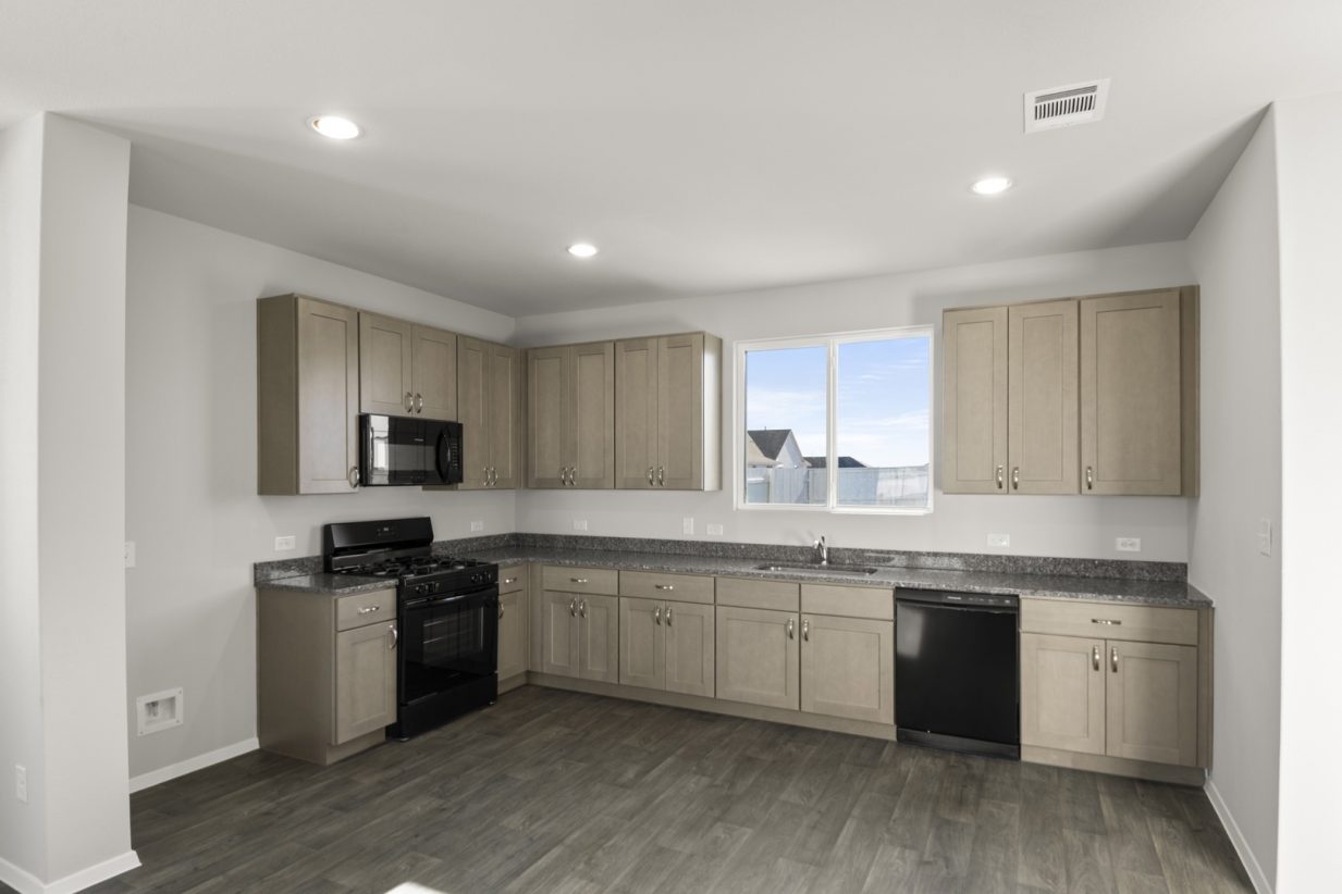 Image of a kitchen with light brown cabinets, granite countertops, black appliances and a window above the sink