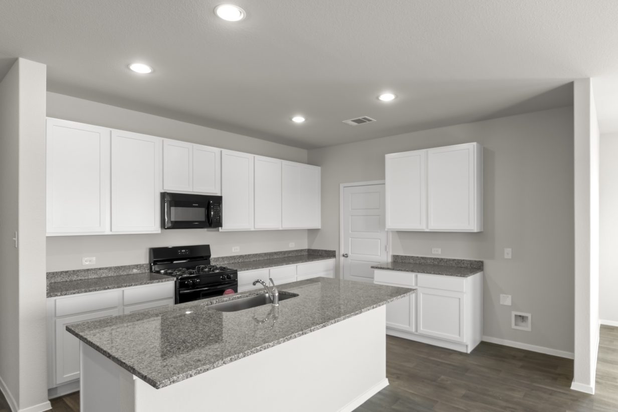 Image of a kitchen with white cabinets, granite countertops, black countertops, and a white center island