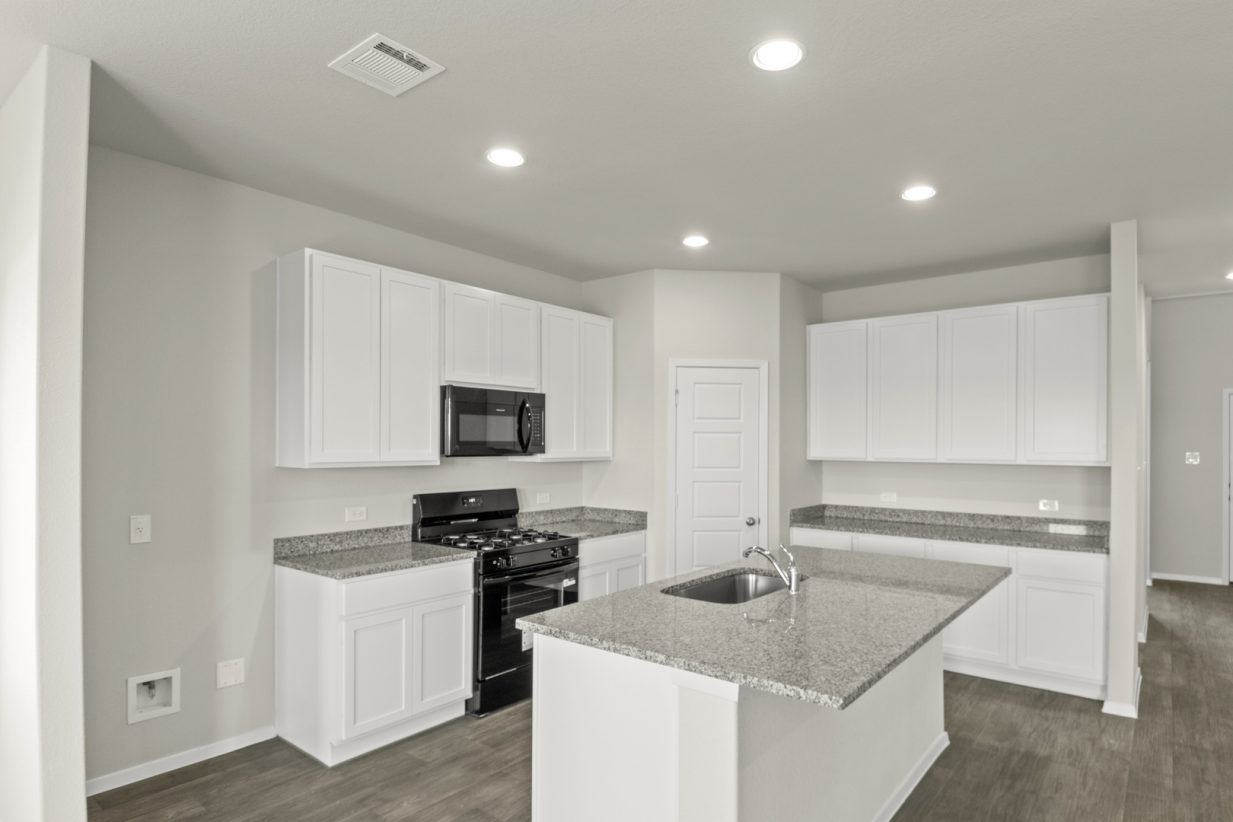 Image of a kitchen with white cabinets, granite countertops, black appliances, a corner pantry