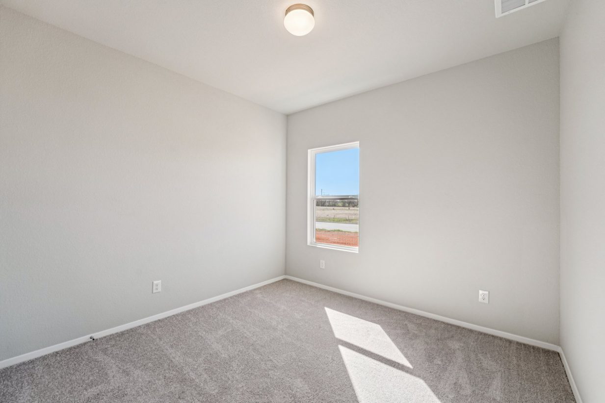 Image of a bedroom with grey walls, carpeting and a window