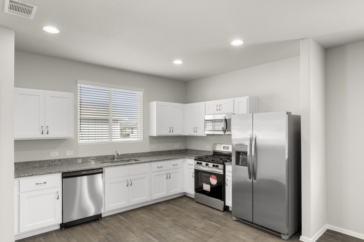 Image of a kitchen with white cabinets, granite countertops, stainless steel appliances, and a window above the sink