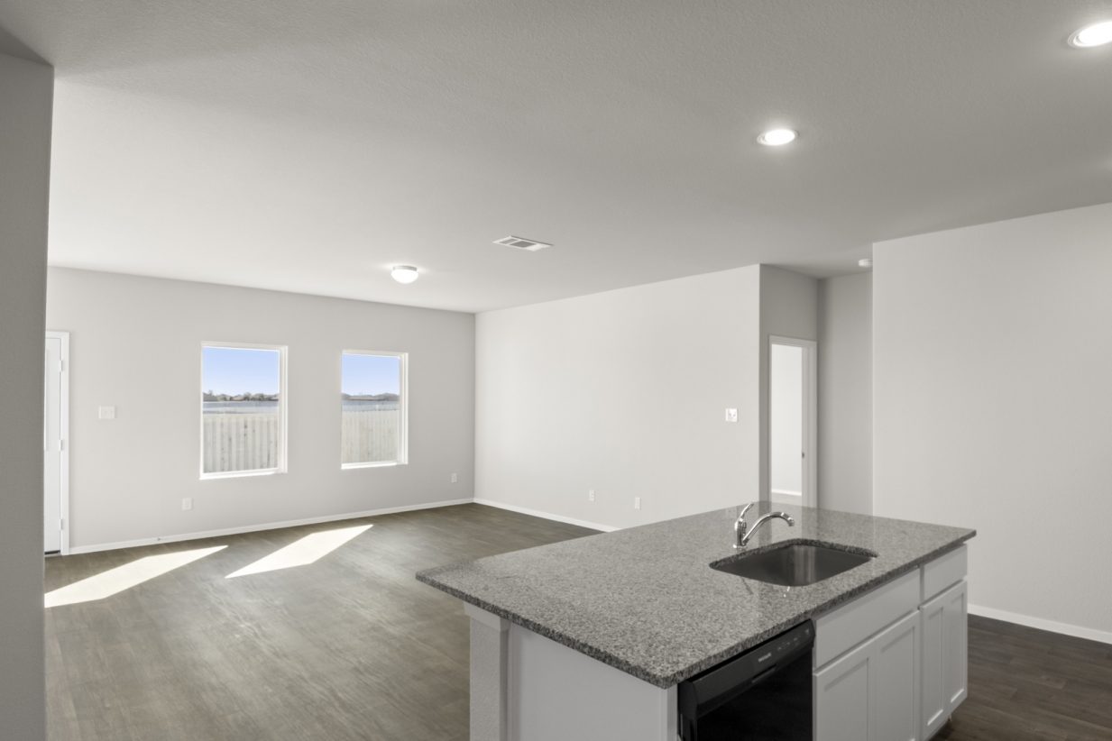 Image of a kitchen with a center island, granite countertops and an overview of the living room
