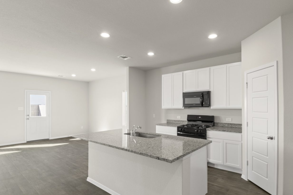 Image of a kitchen with white cabinets, granite counter tops, a center island, black appliances and a corner pantry
