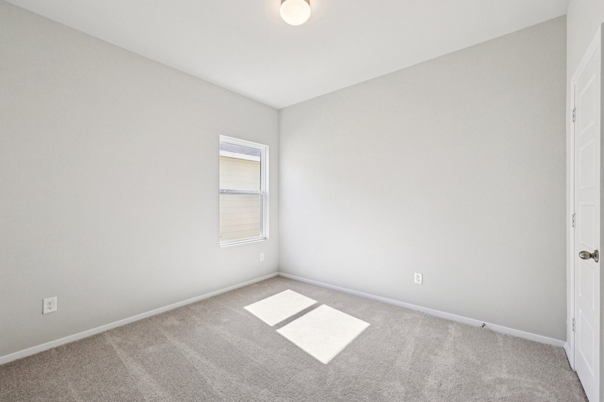 Image of a bedroom with grey walls, tan carpeting, a window and white trim