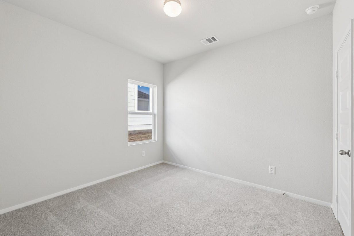 Image of a bedroom with light grey walls, tan carpeting, windows and white trim