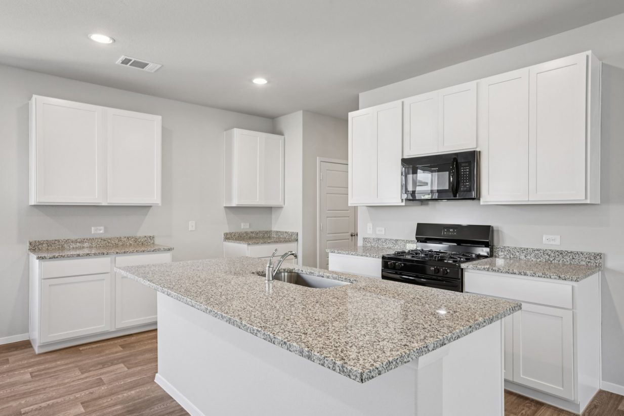 Image of a kitchen with white cabinets, a center island, granite countertops and black appliances
