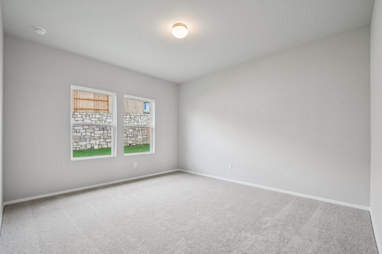 Primary bedroom with large windows, grey walls and tan carpeting