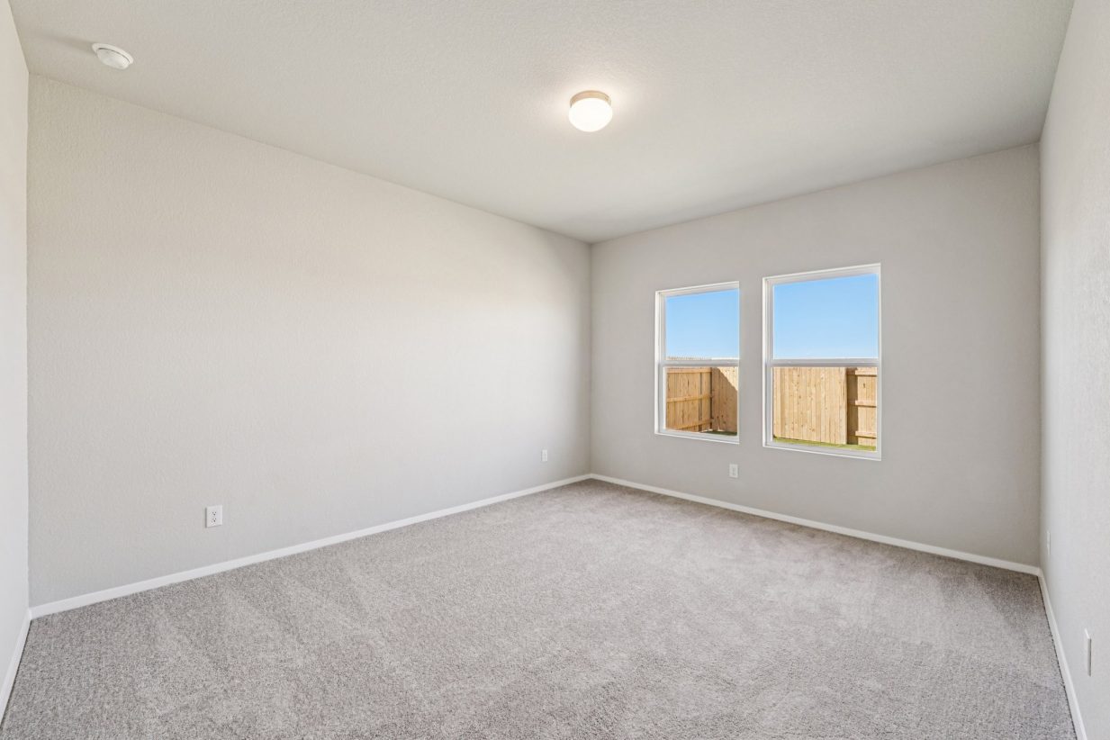 Image of a primary bedroom with grey walls, carpeting and windows