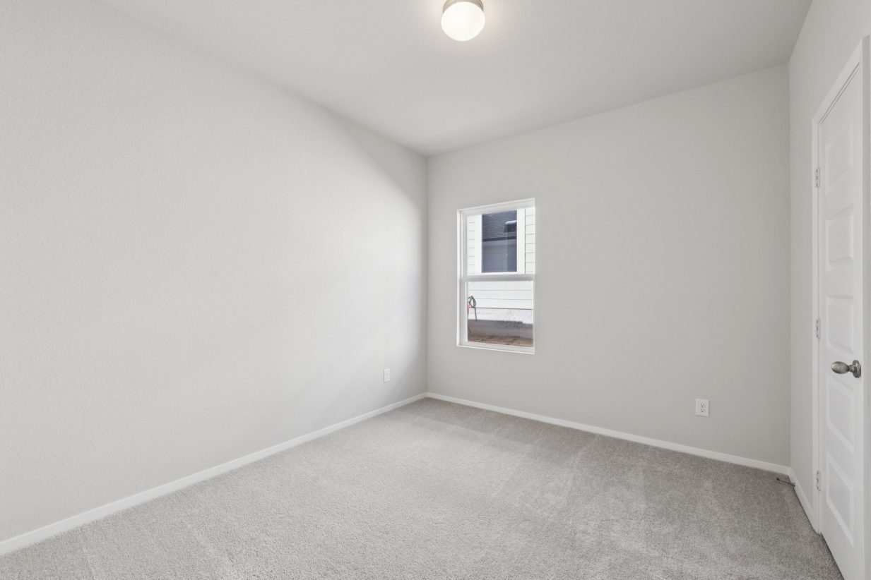 Image of a bedroom with light grey walls and a window