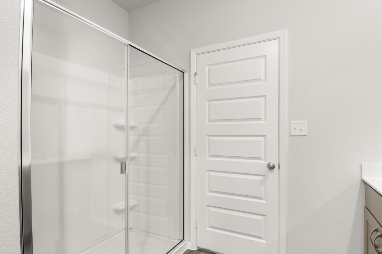 Image of a primary bathroom with a white walk-in shower and a white double vanity