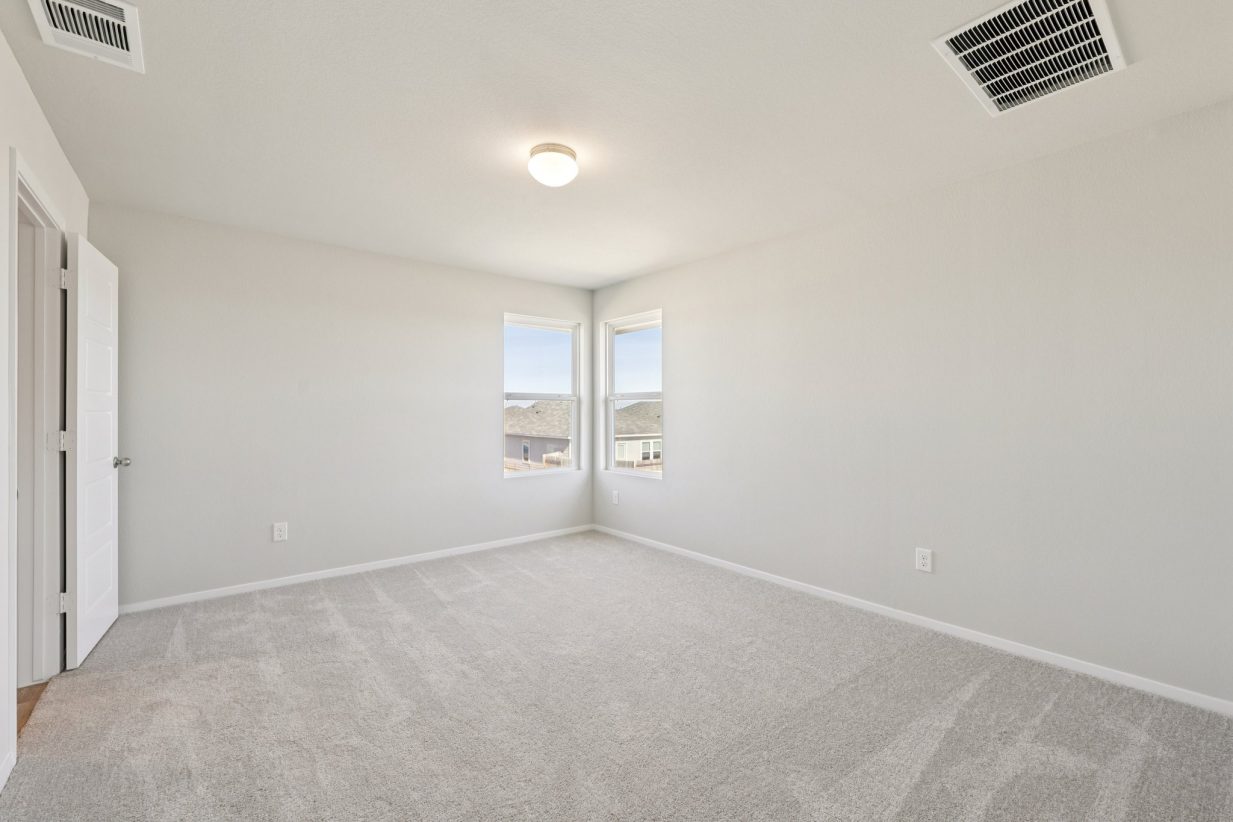 Image of a primary bedroom with tan carpeting, grey walls, windows and white trim