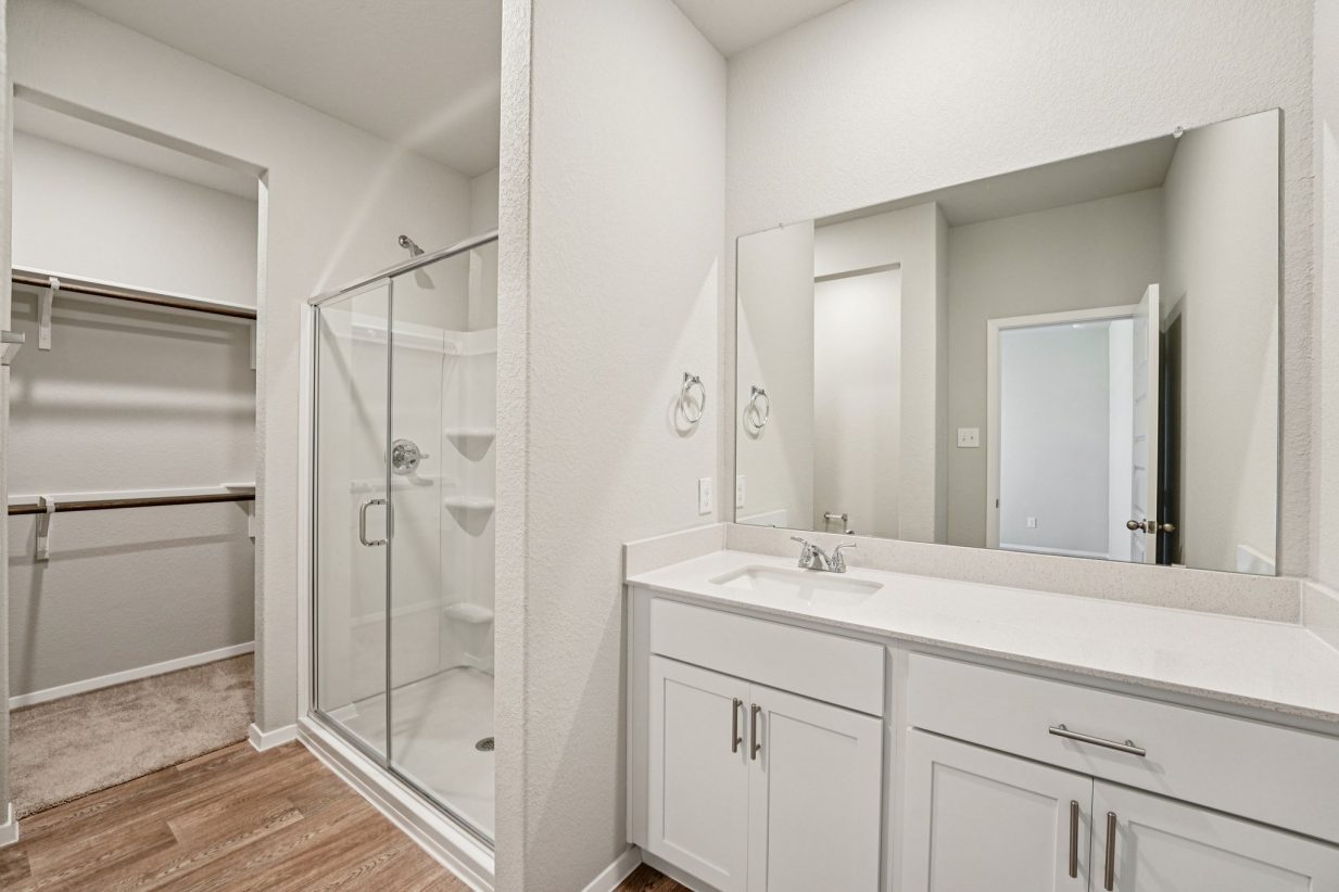 Image of a primary bathroom with a double vanity, a mirror and a standing walk-in shower