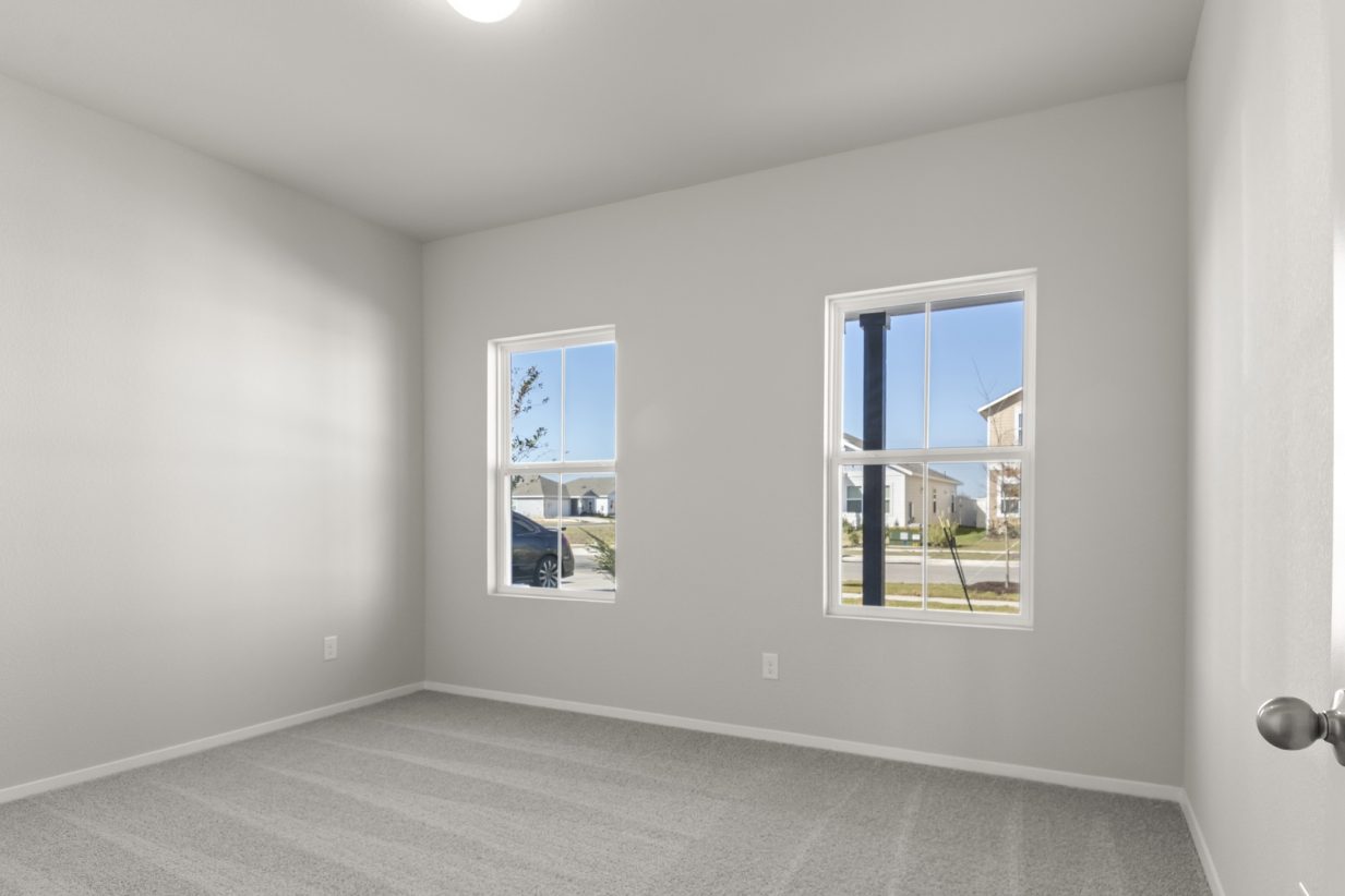 Image of a bedroom with light grey walls, tan carpeting, two windows and white trim