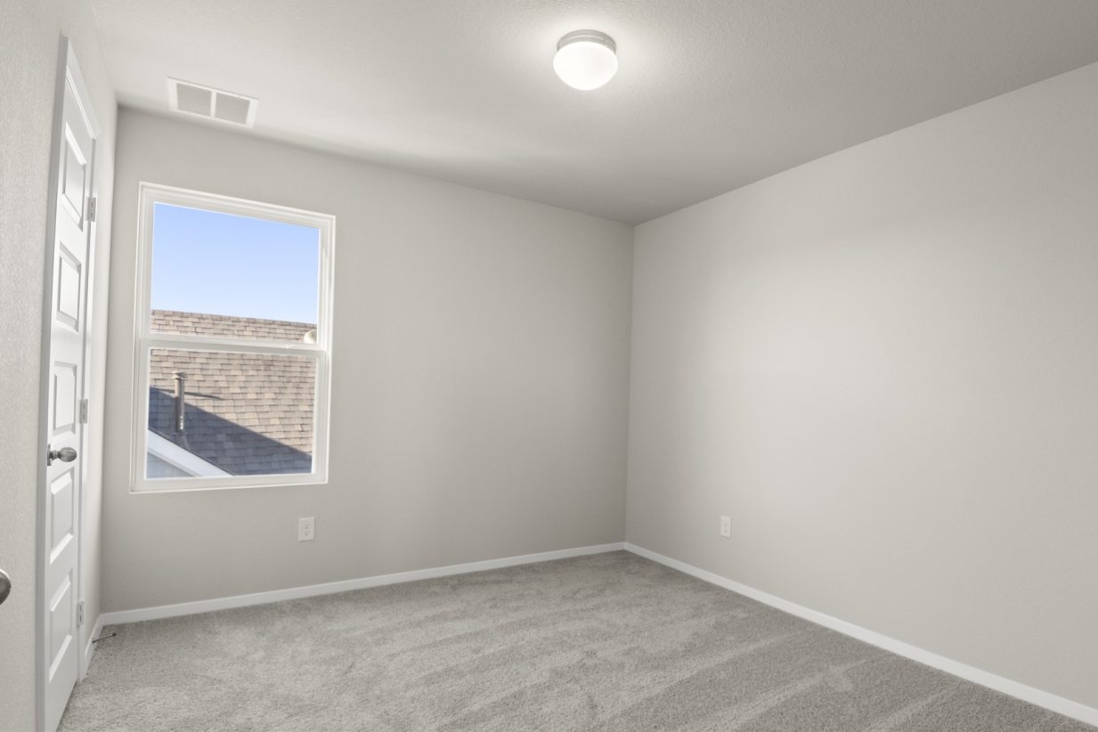 Image of a bedroom with tan carpeting, light grey walls, white trim and a large mirror