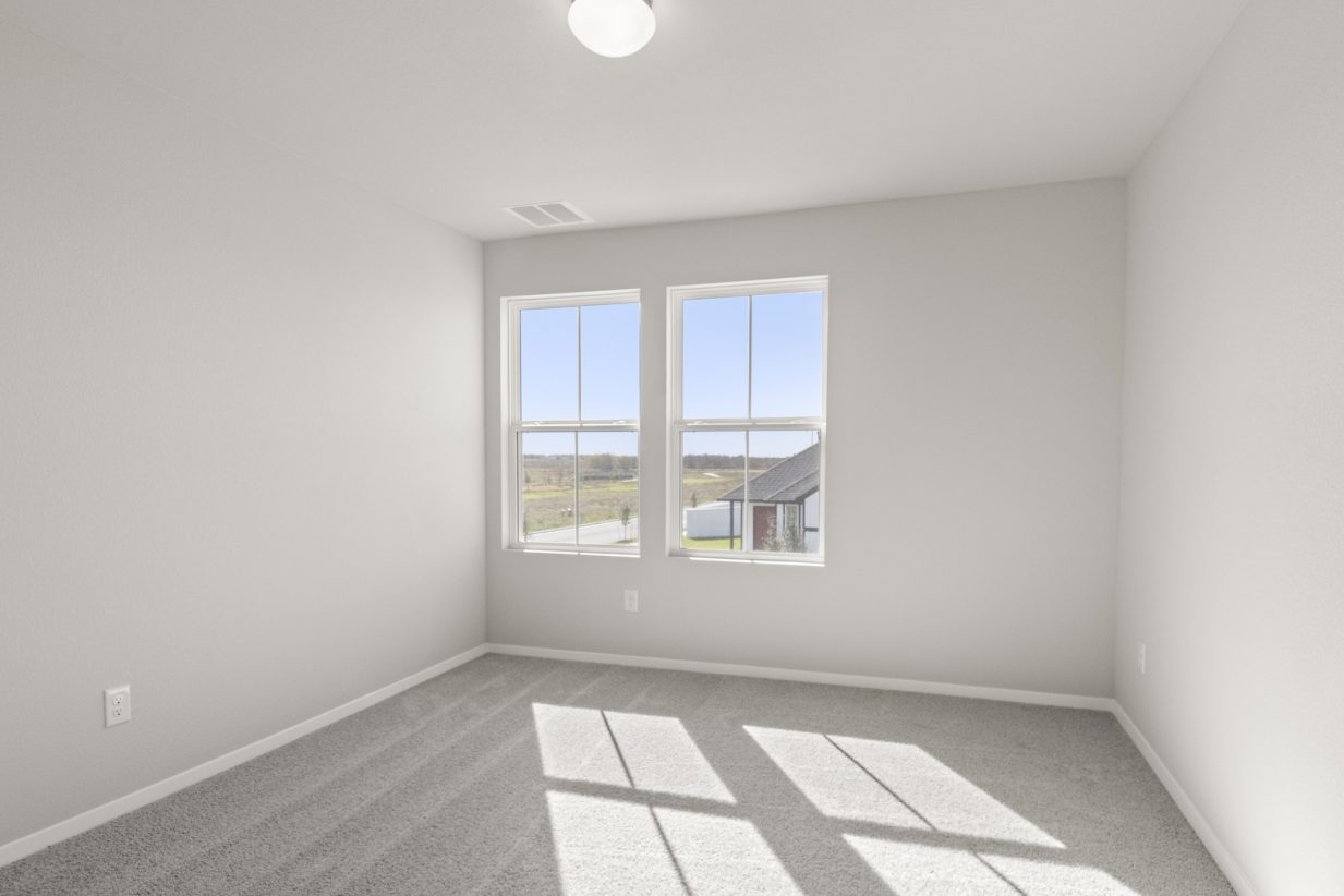 Image of a bedroom with light grey walls, tan carpeting and two windows