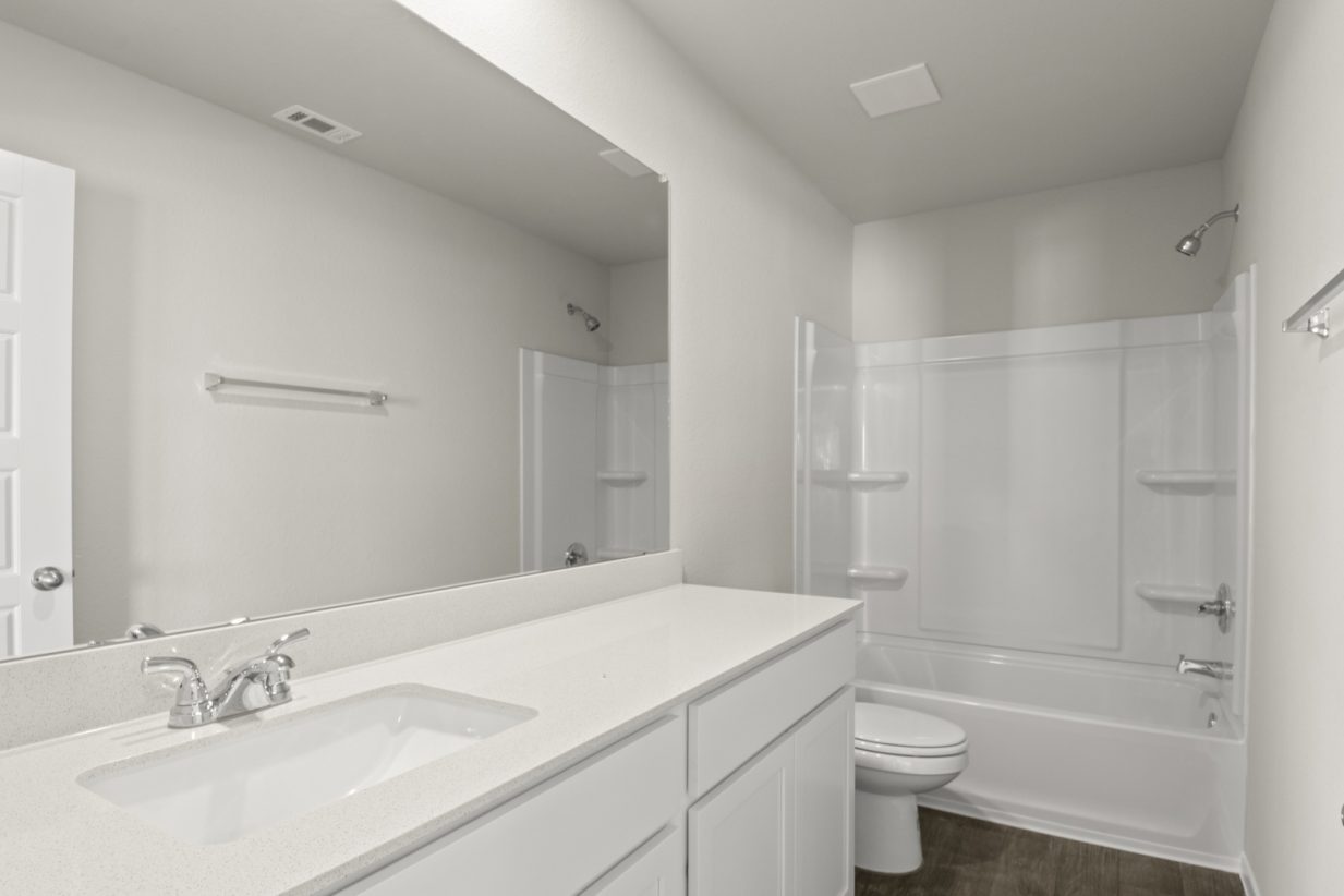 Image of a bathroom with white cabinets, a dual white vanity, a large mirror and a white shower with a tub