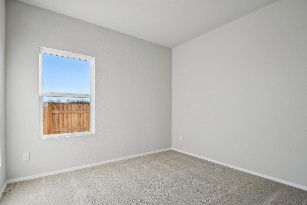 Image of a bedroom with grey walls, tan carpeting and a window with white trim