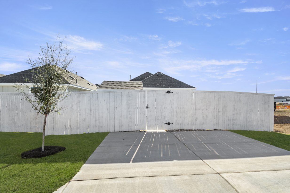 Image of a cement driveway with a white wooden fence