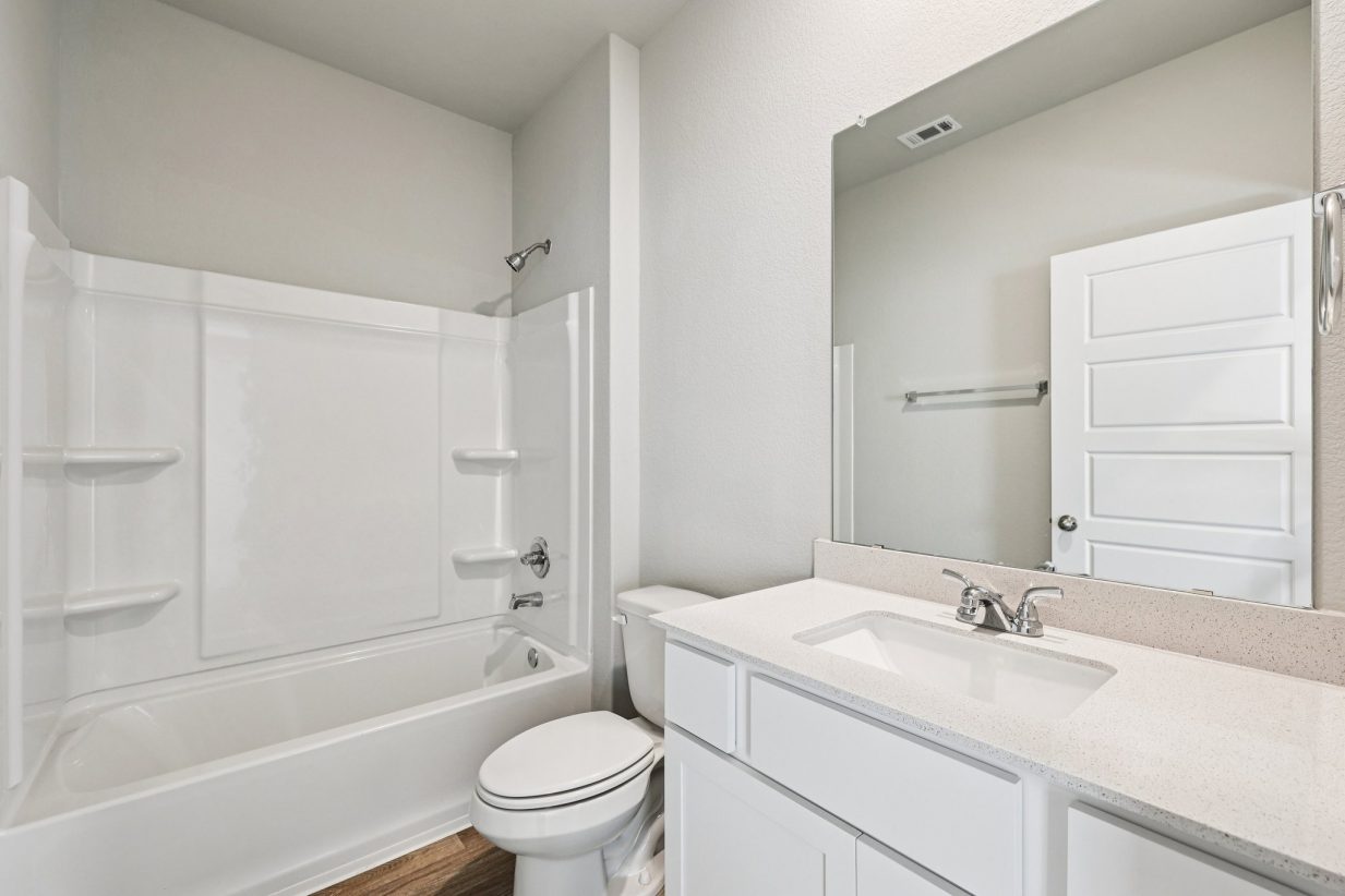 Image of a bathroom with a white dual vanity, large mirror, a shower and tub, and white cabinets