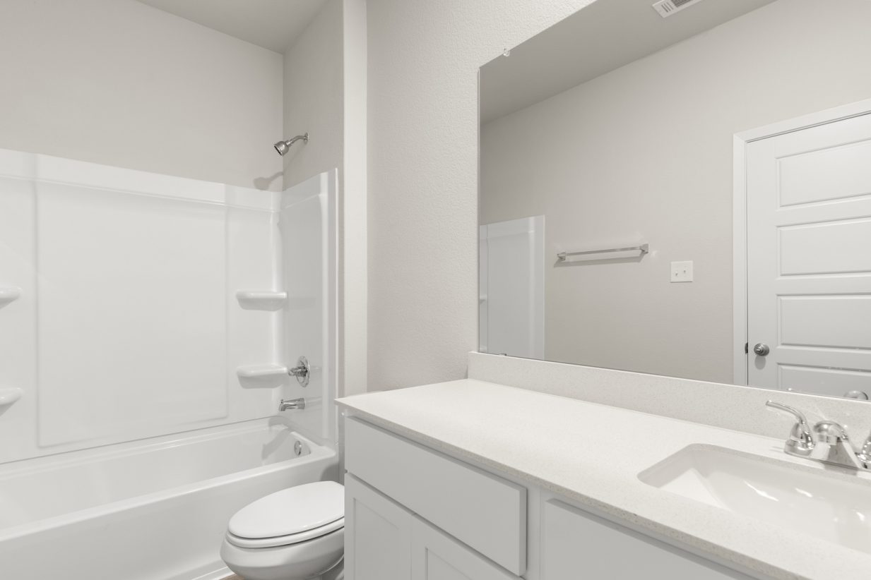 Image of a bedroom with a white double vanity, a large mirror, a white shower with a tub