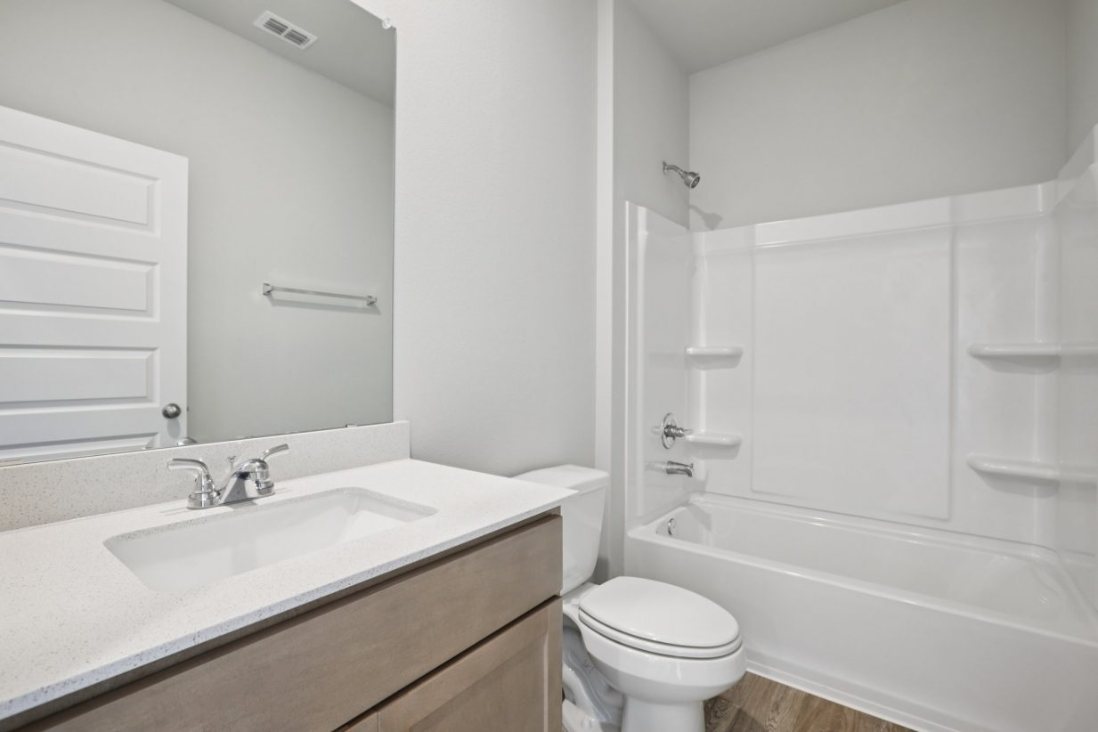Image of a bathroom with a white vanity, a mirror, and a white shower with a tub