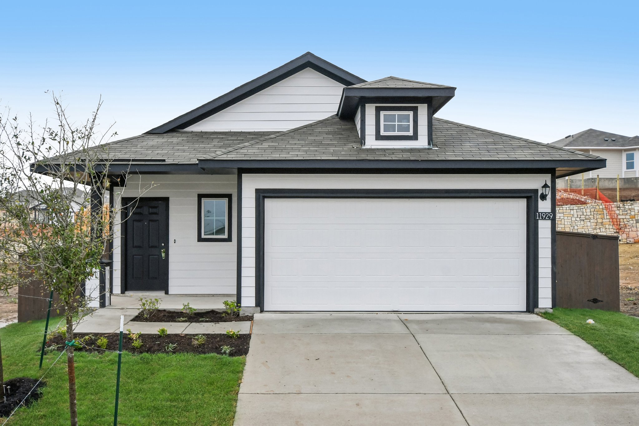 Image of a white one story house front exterior with black trim and front door