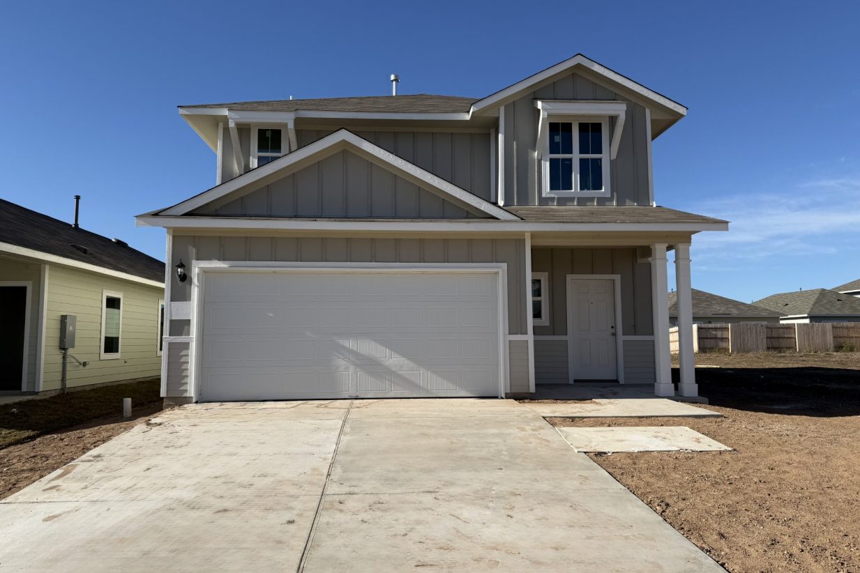 Image of the front exterior of a two story house with a white garage door and a cement driveway