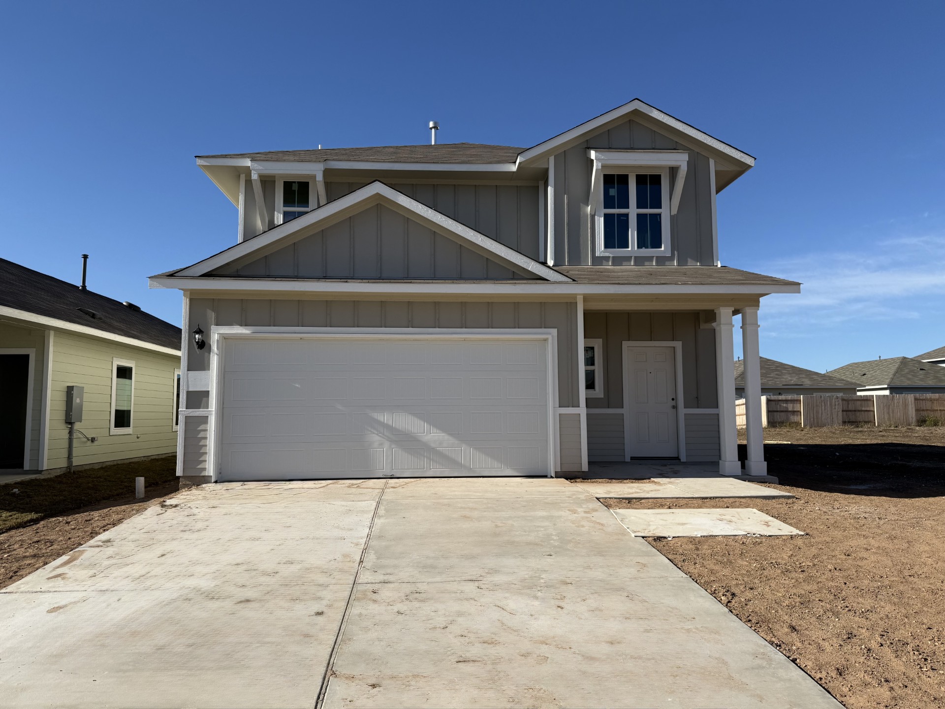 Image of the front exterior of a two story house with a white garage door and a cement driveway