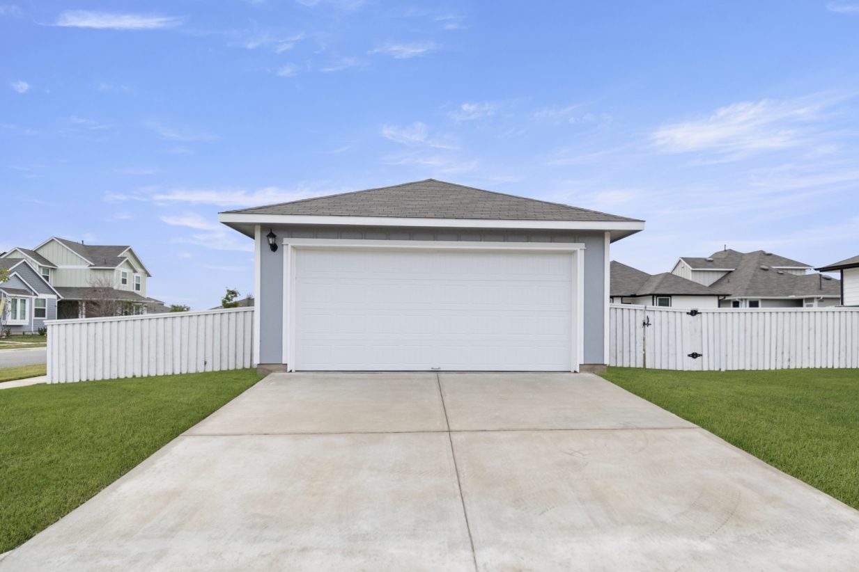 Image of an ally access garage exterior with a white door and a cement driveway