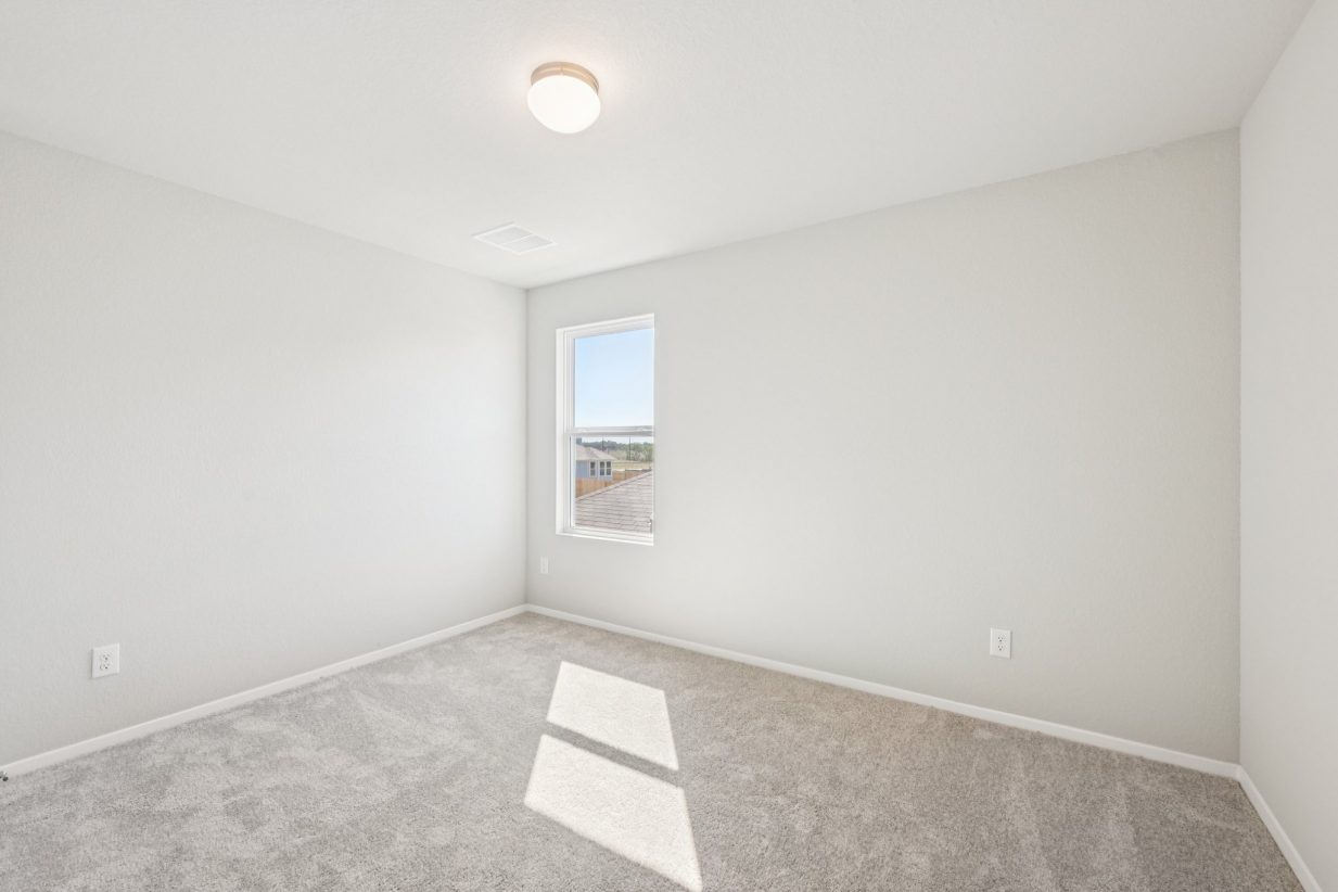 Image of a primary bedroom with beige walls, carpeting and a window
