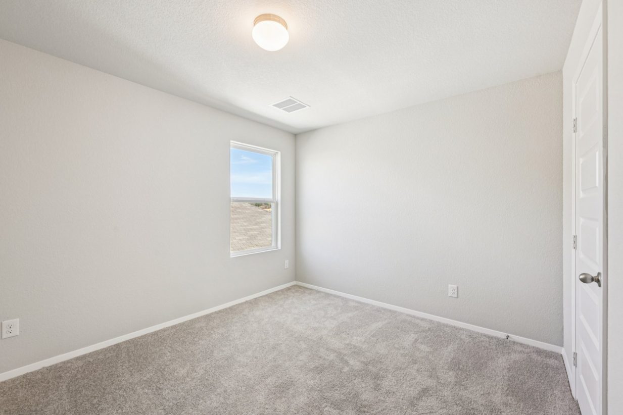 Image of a primary bedroom with beige walls, carpeting and a window