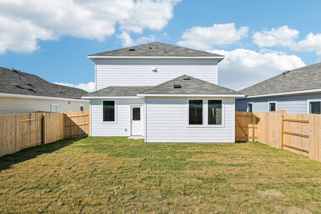 Image of a blue two story house back exterior with a green grass backyard