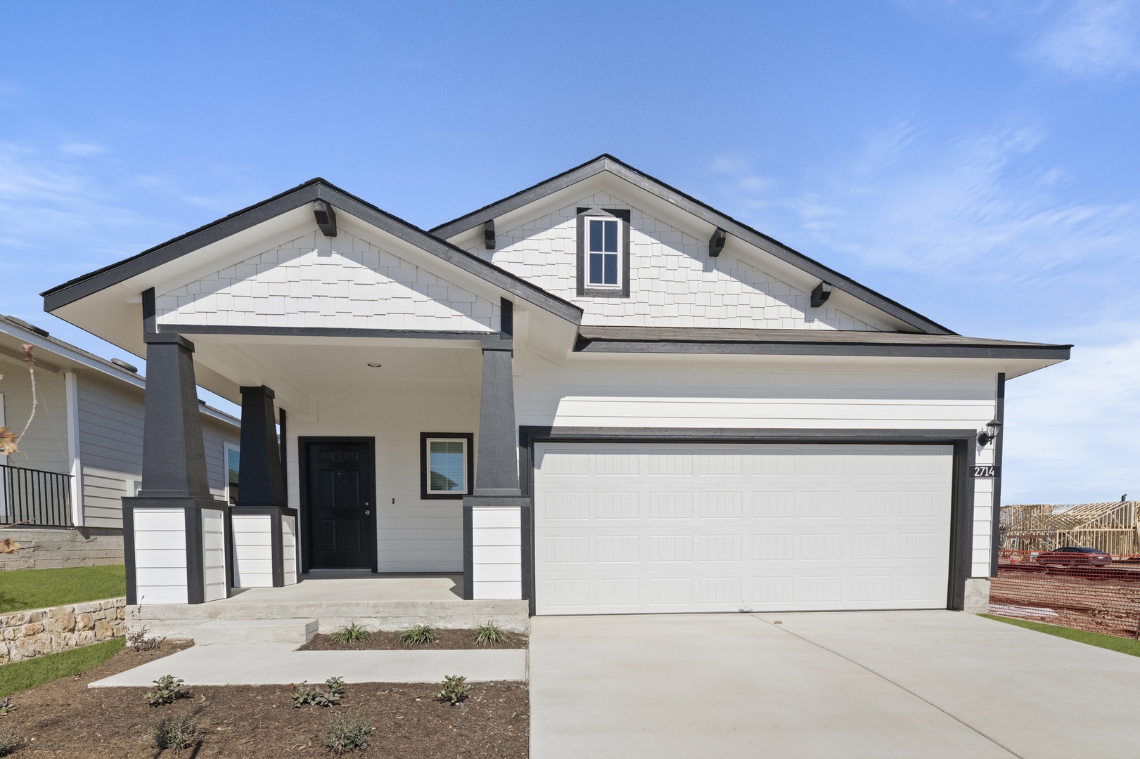 Image of a white one story house with black trim, a black front door, and a blue sky in the background