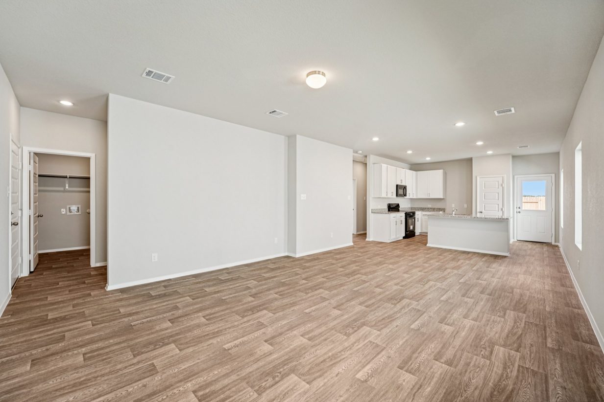 Image of a living and dining area with vinyl flooring, grey walls and windows